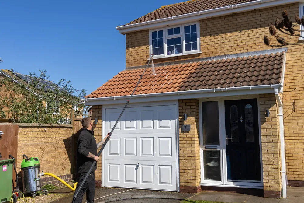 Safe'N'Clean operative using a water-fed pole to clean upstairs windows on a detached house