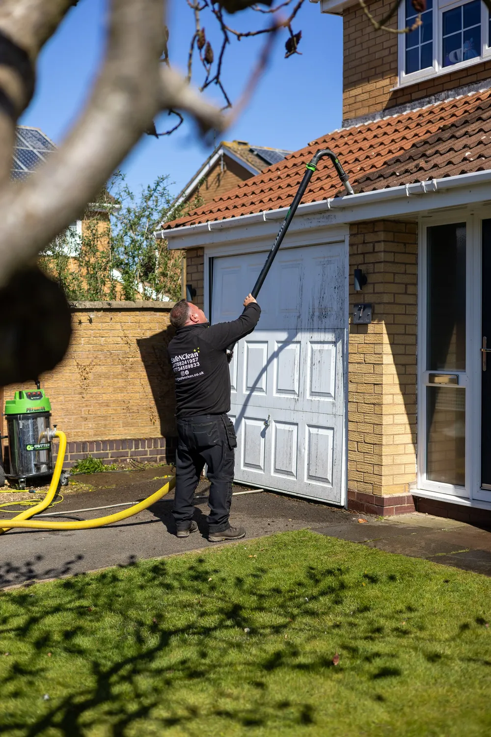 Safe'N'Clean van hose reel and pole set up on a driveway while windows are cleaned